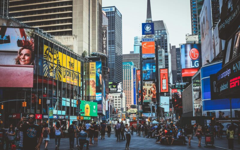 Bustling daytime view of Times Square with crowds, skyscrapers, and iconic billboards in New York City.